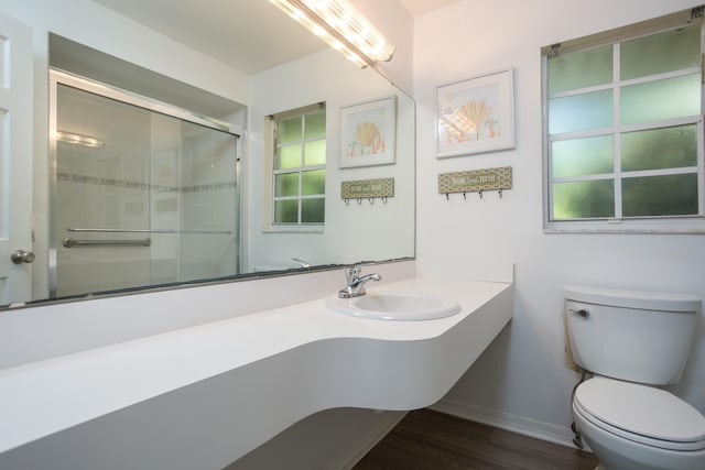 bathroom featuring hardwood / wood-style flooring, walk in shower, vanity, and toilet