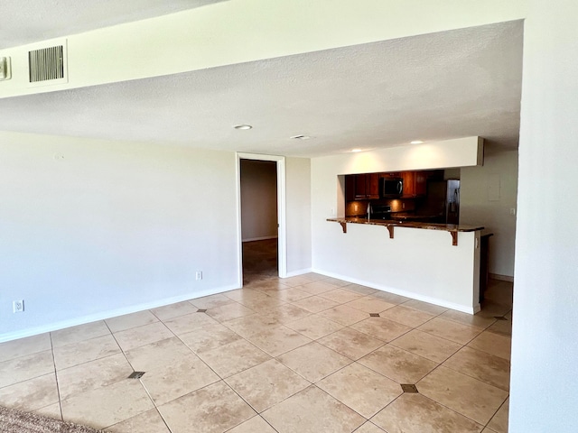 unfurnished room featuring light tile patterned floors, baseboards, visible vents, and a textured ceiling