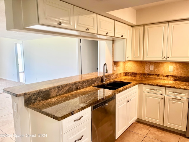 kitchen featuring stainless steel dishwasher, sink, white cabinets, light tile patterned floors, and dark stone counters