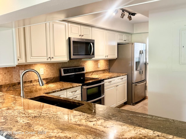 kitchen with tasteful backsplash, track lighting, appliances with stainless steel finishes, and light tile patterned floors