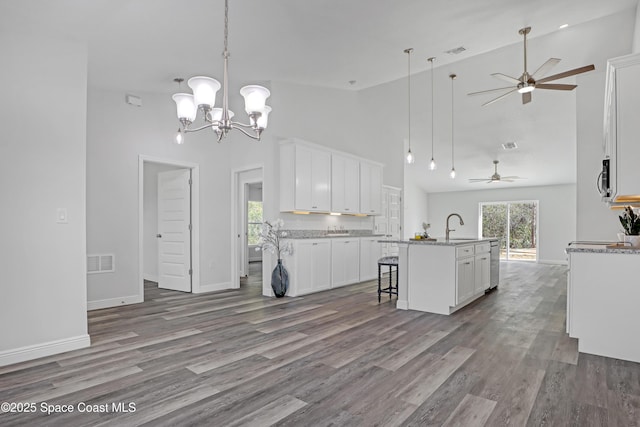 kitchen with an island with sink, wood finished floors, and white cabinetry