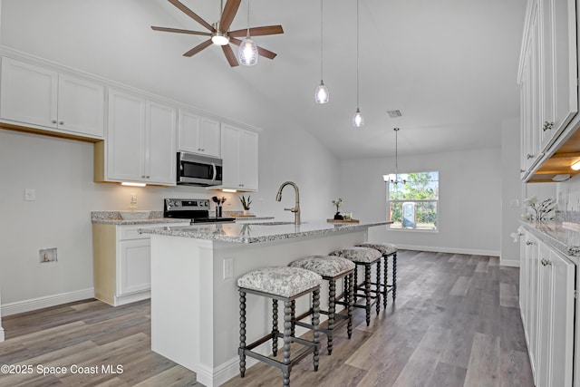 kitchen featuring stainless steel appliances, light wood-type flooring, white cabinets, and light stone counters