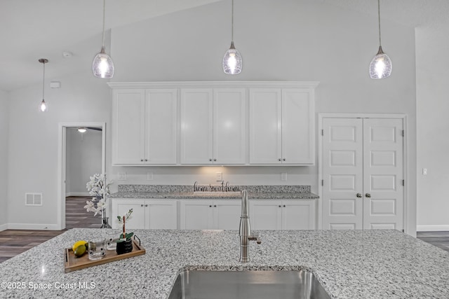 kitchen with visible vents, high vaulted ceiling, white cabinets, and a sink