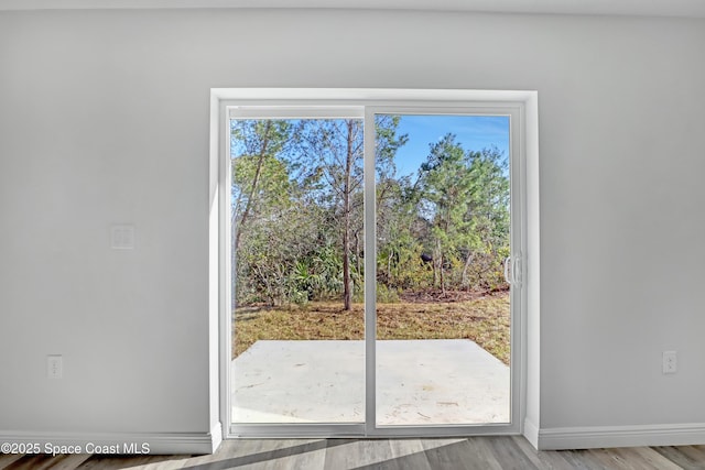 doorway with baseboards and wood finished floors