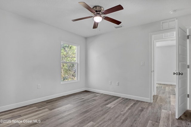 spare room featuring wood finished floors, visible vents, and baseboards