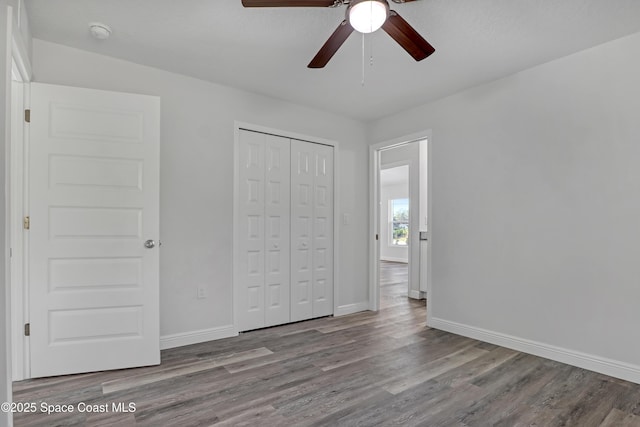 unfurnished bedroom featuring a ceiling fan, a closet, baseboards, and wood finished floors