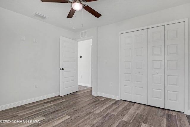 unfurnished bedroom with a closet, visible vents, baseboards, and wood finished floors