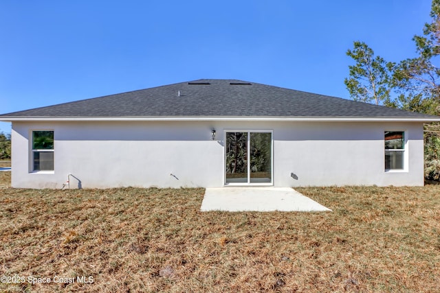 rear view of property with stucco siding, a patio, a lawn, and roof with shingles