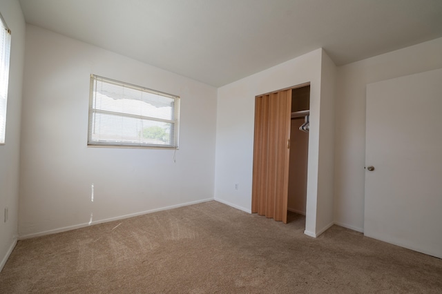 unfurnished bedroom with light carpet and a closet