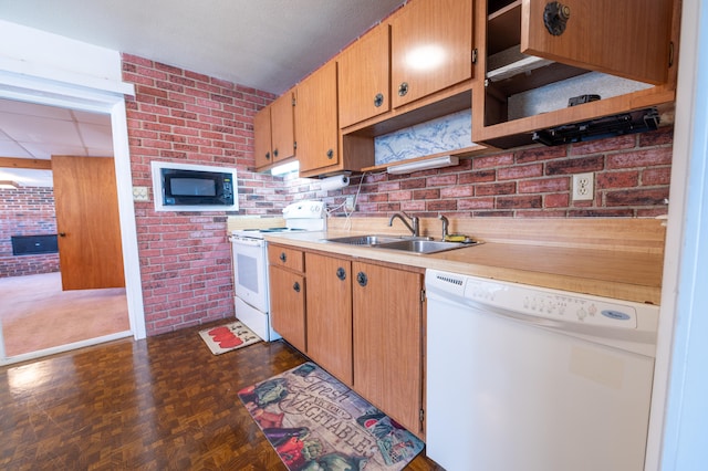 kitchen featuring brick wall, white appliances, dark parquet floors, and sink