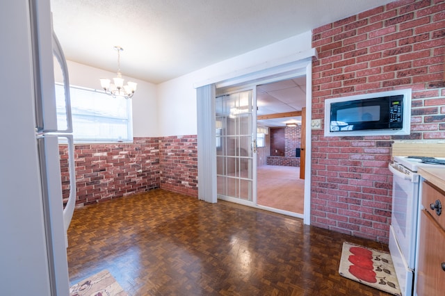 interior space featuring dark parquet flooring, brick wall, and an inviting chandelier