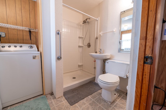 bathroom with tiled shower, washer / dryer, toilet, and tile patterned floors