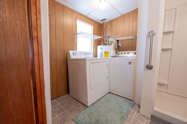 laundry area with wood walls, washer and clothes dryer, and electric water heater