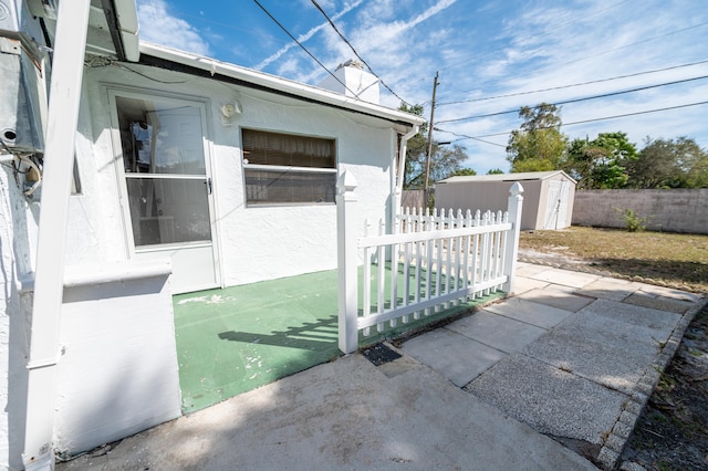 view of side of home with a patio area and a storage shed