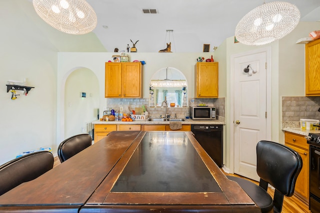 kitchen featuring decorative light fixtures, a notable chandelier, black appliances, backsplash, and sink