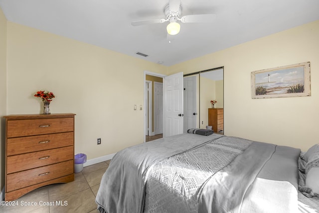 tiled bedroom with ceiling fan and a closet