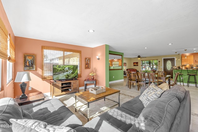 living room with ceiling fan, light tile patterned flooring, and a healthy amount of sunlight