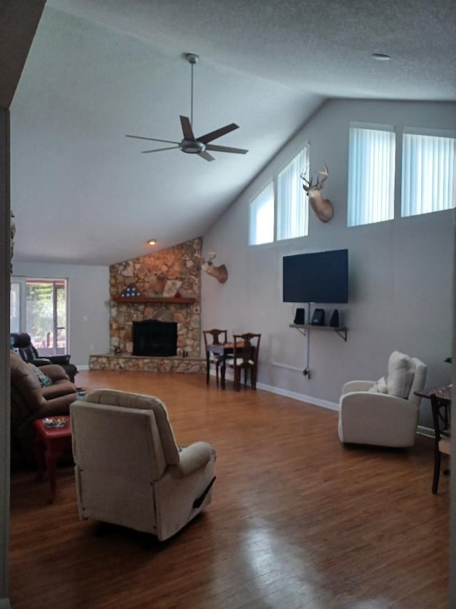 living room featuring a wealth of natural light, vaulted ceiling, a stone fireplace, and dark hardwood / wood-style flooring