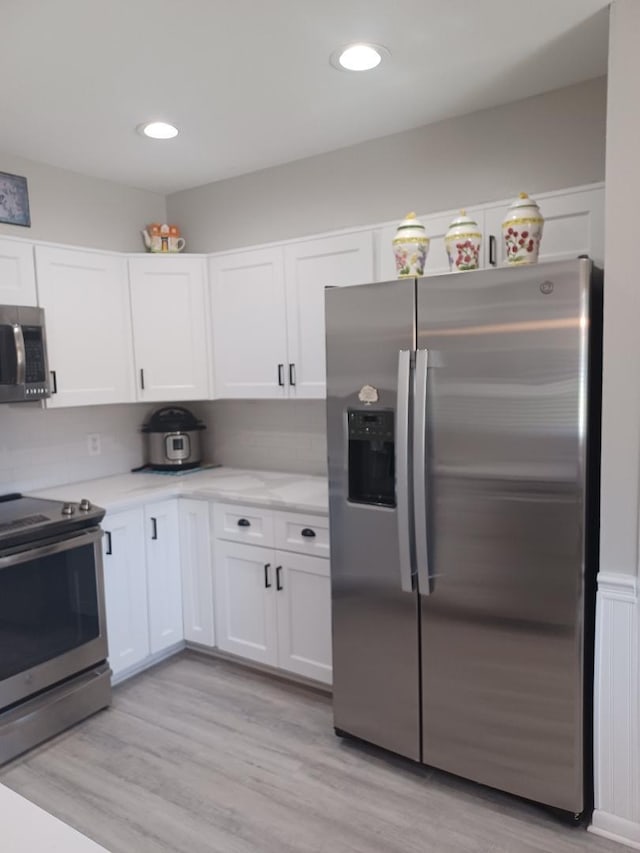 kitchen with light hardwood / wood-style floors, white cabinets, and stainless steel appliances