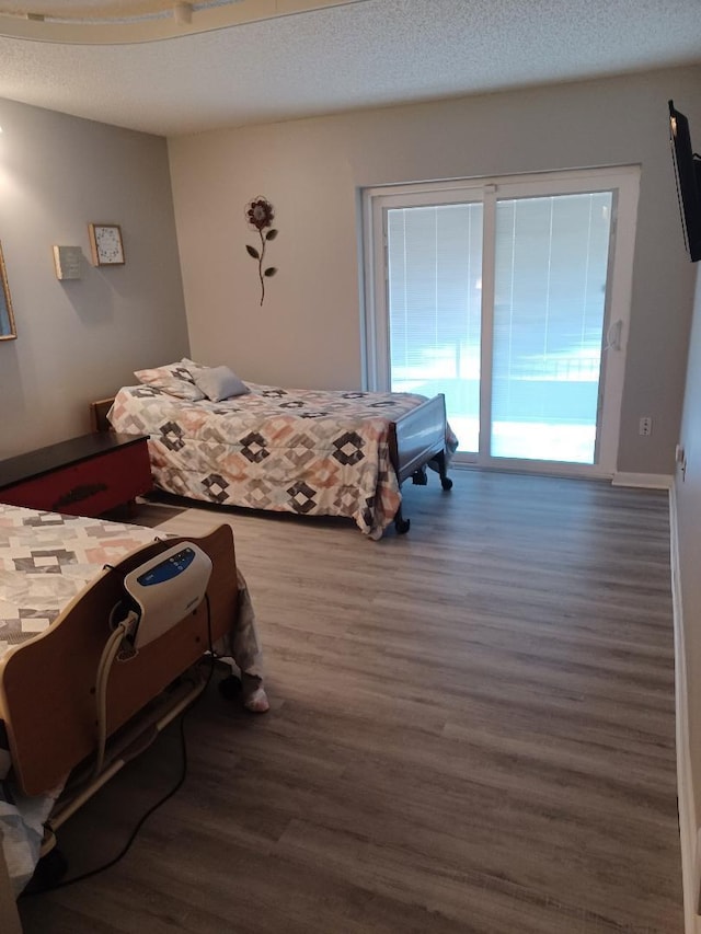 bedroom featuring a textured ceiling, access to exterior, and dark hardwood / wood-style flooring