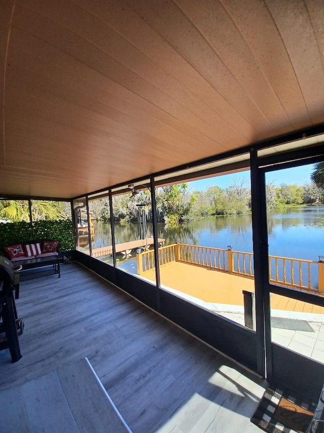 unfurnished sunroom featuring a water view and wood ceiling