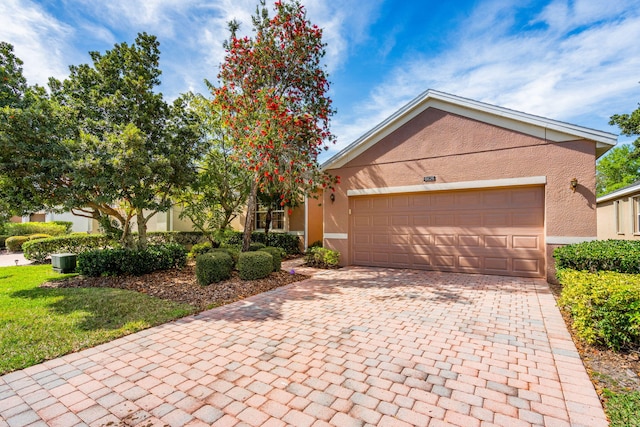 view of front of property featuring a front lawn, a garage, and central air condition unit