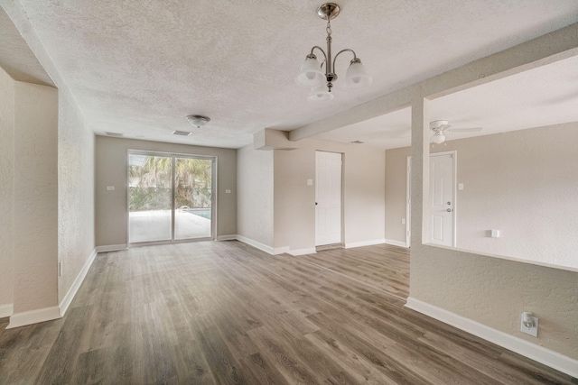 empty room featuring a textured ceiling, dark hardwood / wood-style floors, and ceiling fan with notable chandelier