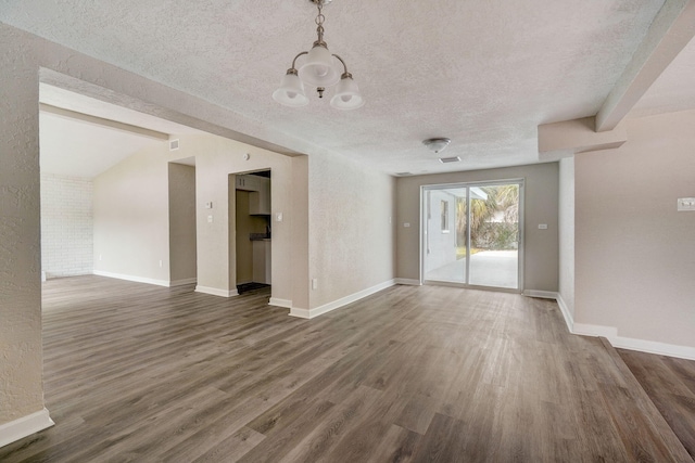 spare room with an inviting chandelier, a textured ceiling, vaulted ceiling, and dark hardwood / wood-style flooring