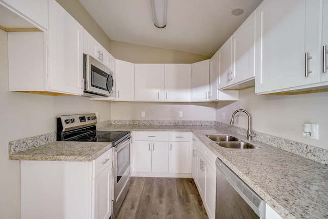 kitchen with stainless steel appliances, light hardwood / wood-style floors, sink, white cabinetry, and light stone countertops