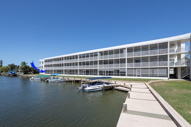 view of dock featuring a balcony, a yard, and a water view