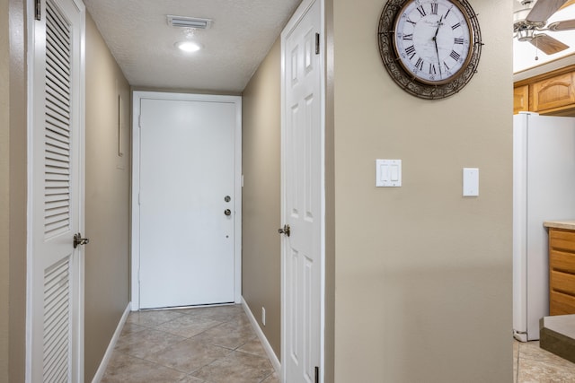 hall with light tile floors and a textured ceiling