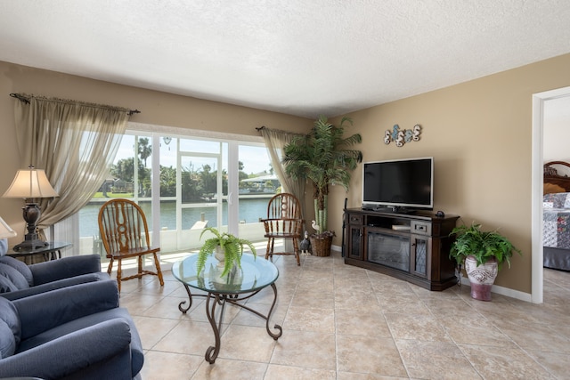 tiled living room featuring a textured ceiling and a water view