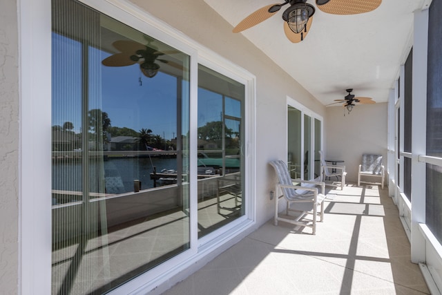 sunroom featuring ceiling fan and a water view