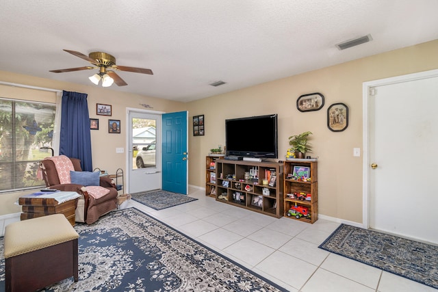 tiled living room with ceiling fan and a textured ceiling