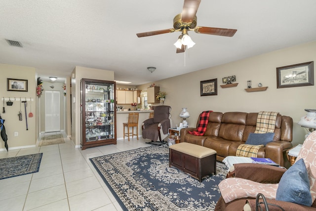 living room with light tile floors, a textured ceiling, and ceiling fan