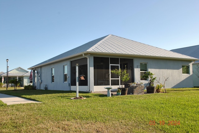 rear view of property with a lawn and a sunroom