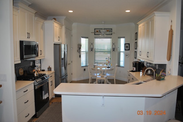 kitchen featuring kitchen peninsula, dark hardwood / wood-style flooring, appliances with stainless steel finishes, tasteful backsplash, and white cabinetry