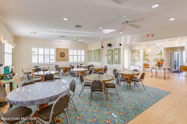 dining space with light hardwood / wood-style floors, ceiling fan, and rail lighting