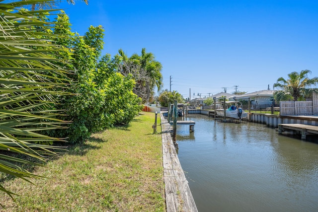 view of dock with a yard and a water view