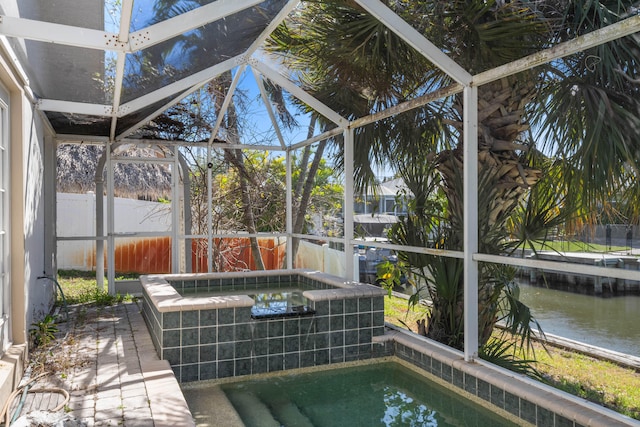 view of swimming pool featuring glass enclosure and a water view