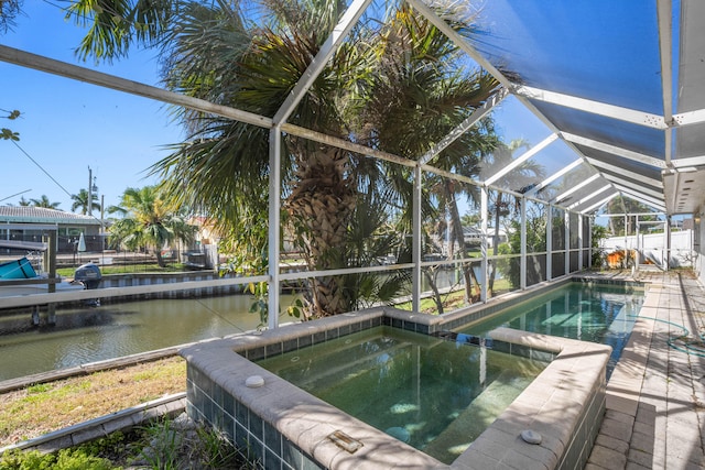 view of pool featuring an in ground hot tub, glass enclosure, a water view, and a patio