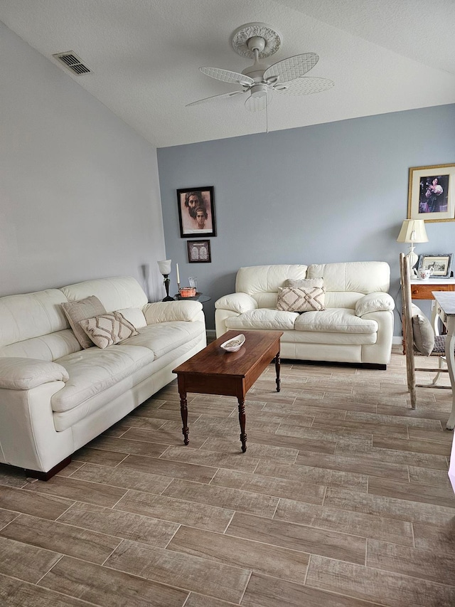 living room with a textured ceiling, wood-type flooring, and ceiling fan