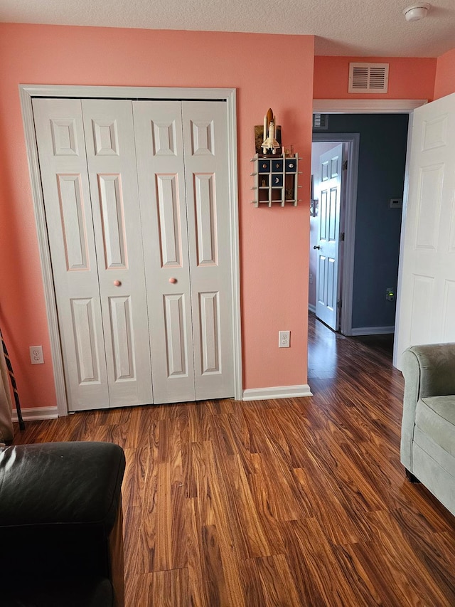 interior space featuring a textured ceiling and dark wood-type flooring