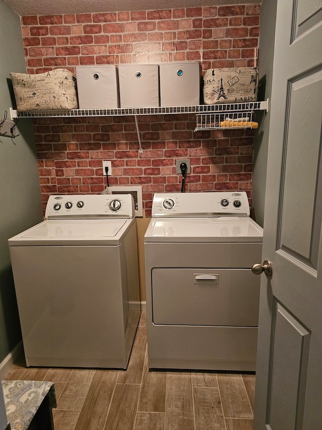 laundry room featuring brick wall, hookup for an electric dryer, and independent washer and dryer