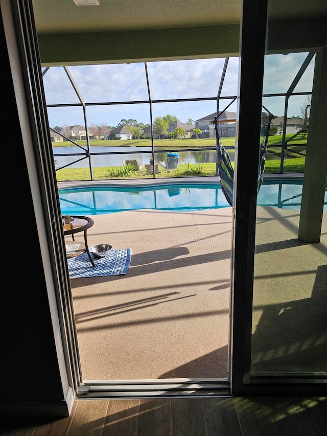 view of pool with glass enclosure and a water view