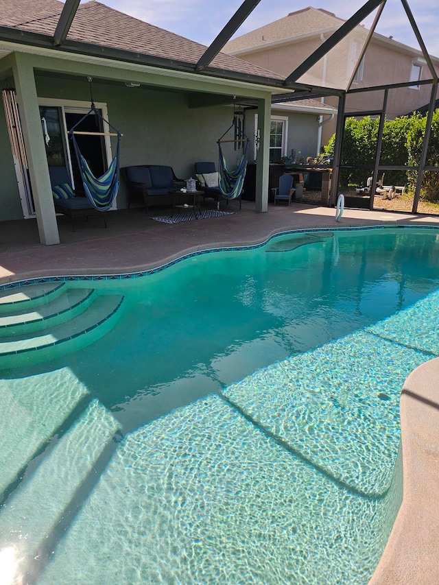 view of swimming pool featuring outdoor lounge area, a patio, and a lanai