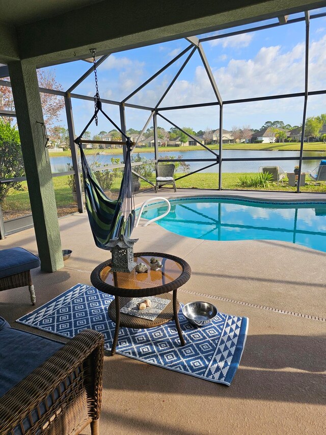 view of swimming pool with glass enclosure, a patio, and a water view