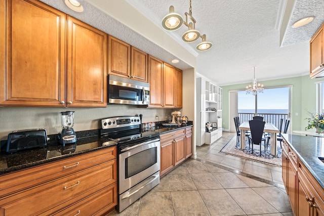 kitchen with light tile floors, stainless steel appliances, dark stone countertops, a notable chandelier, and a textured ceiling