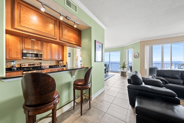 kitchen with a water view, stainless steel appliances, a textured ceiling, crown molding, and rail lighting