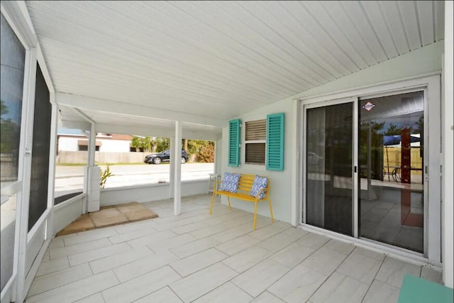 unfurnished sunroom featuring vaulted ceiling